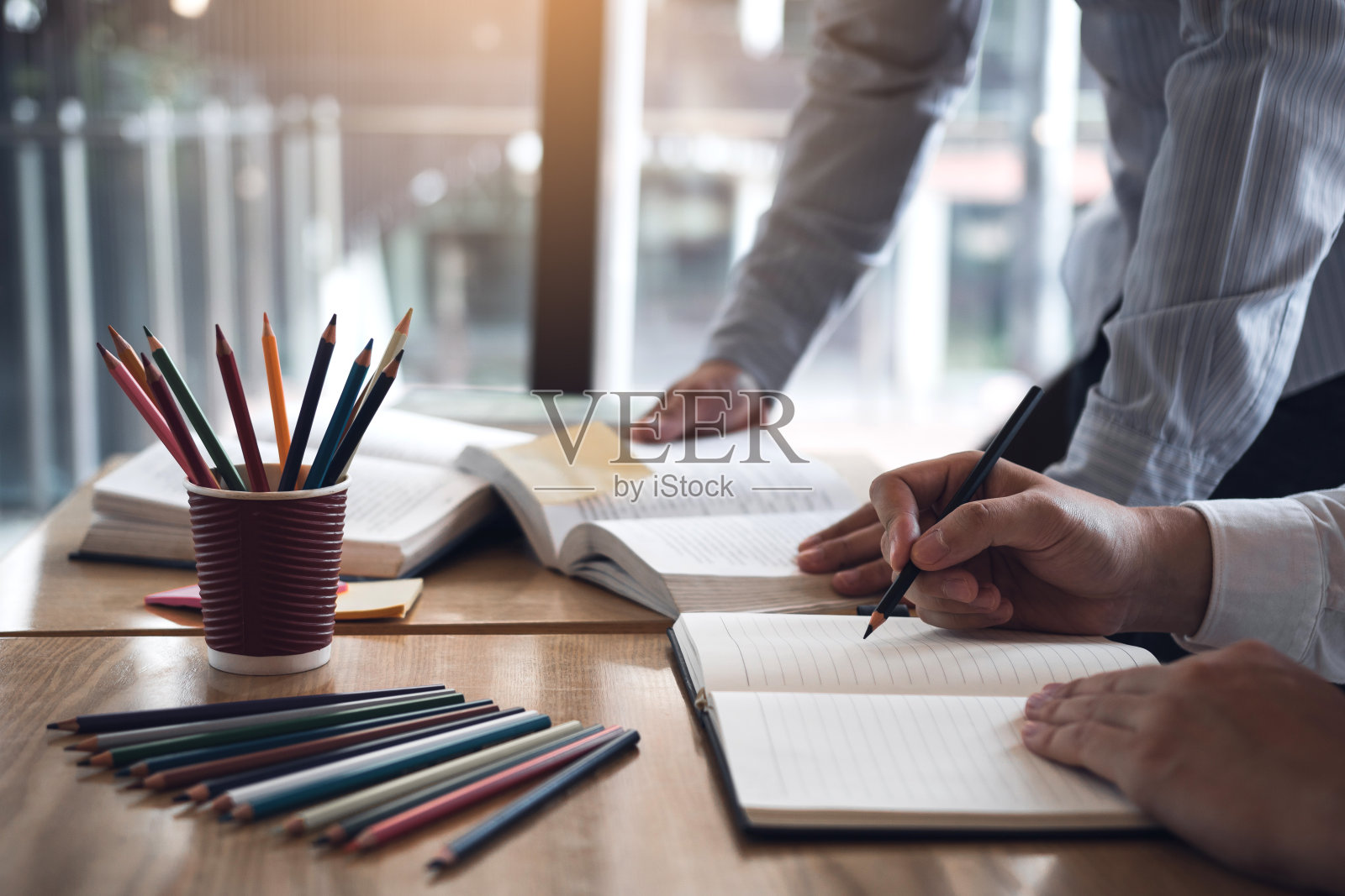 两个学生在图书馆一起阅读考试教材。照片摄影图片