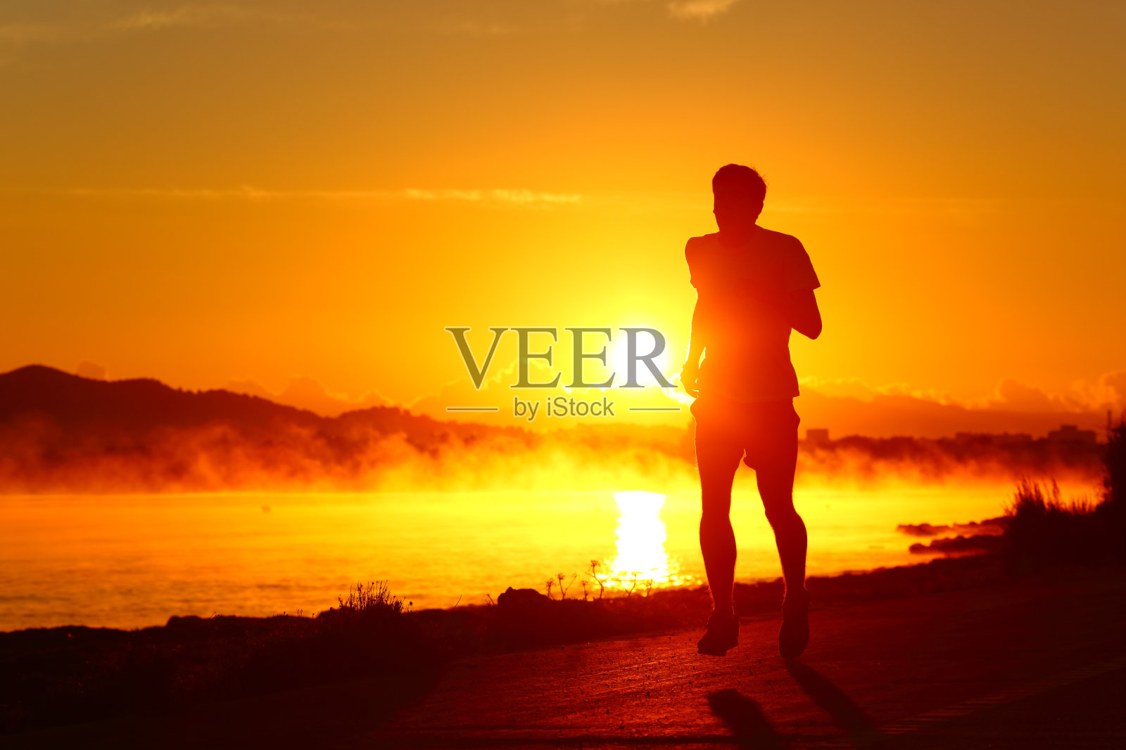 跑步者的剪影在日落时在海滩上跑步照片摄影图片