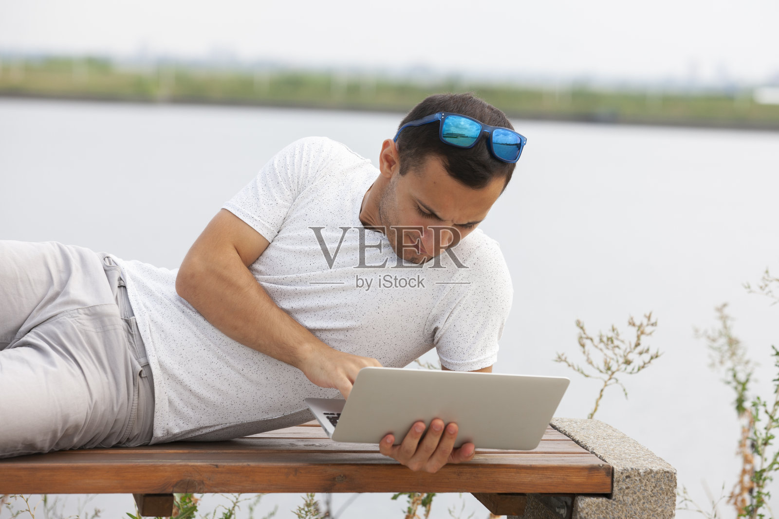 一个年轻人坐在办公室外面，拿着笔记本电脑照片摄影图片