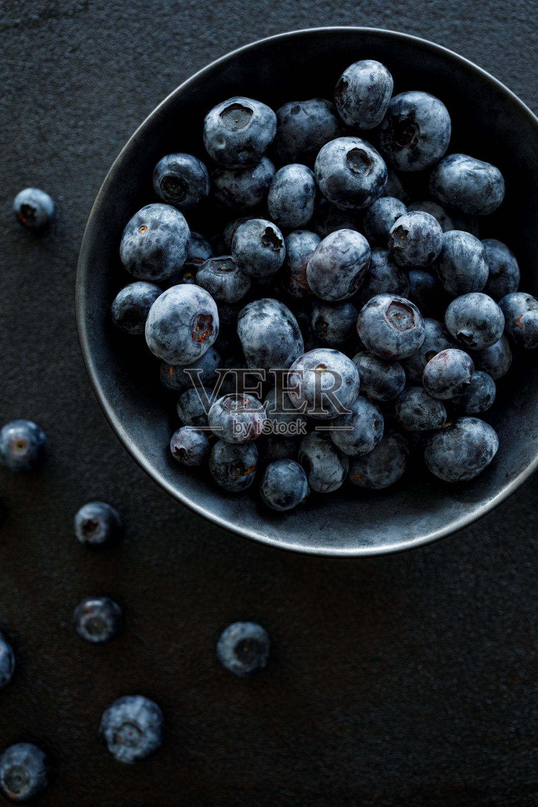 新鲜的蓝莓放在黑色的陶瓷碗里，背景是黑色，俯视图照片摄影图片