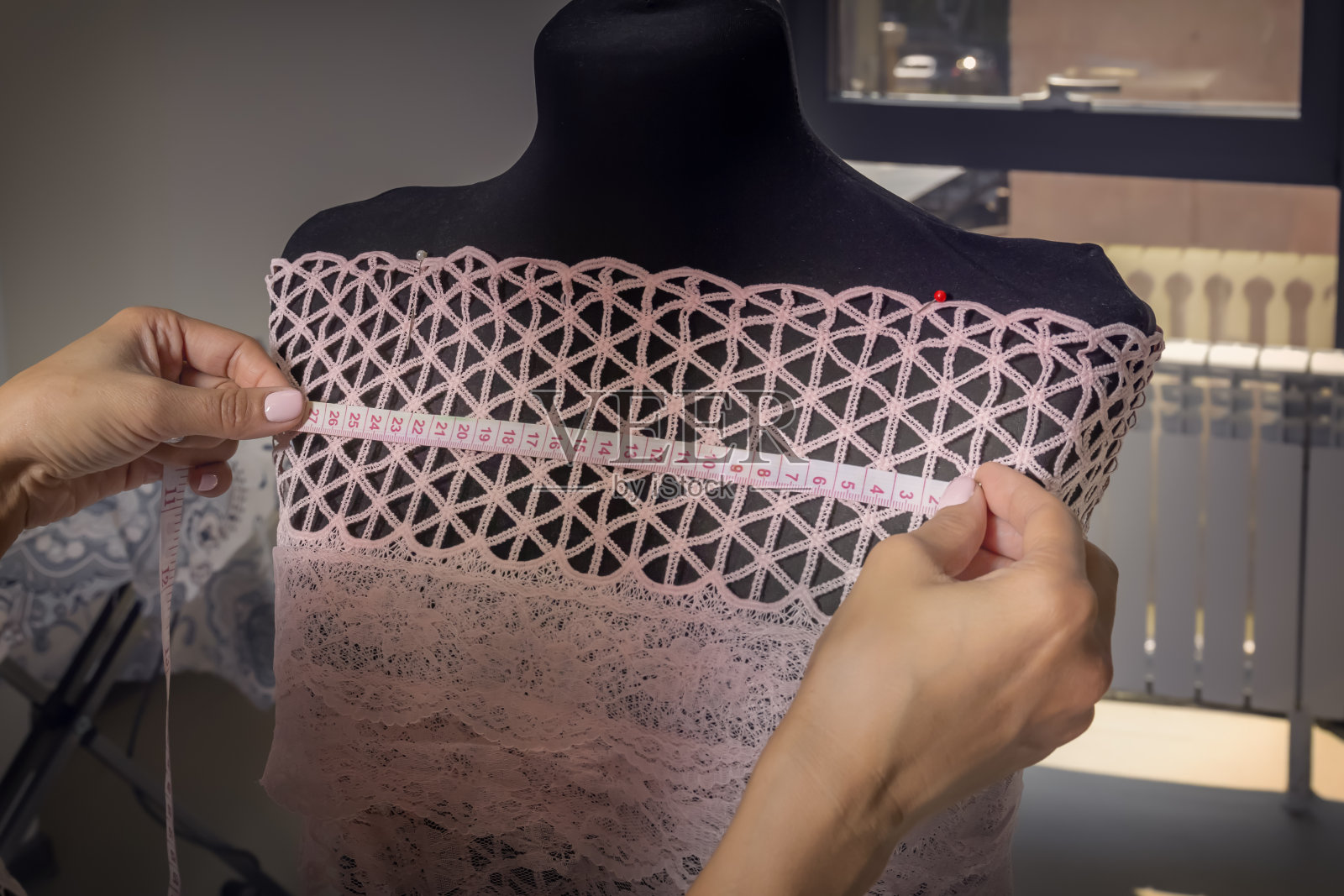 一个女裁缝在车间里为一个人体模特量衣服。特写镜头照片摄影图片