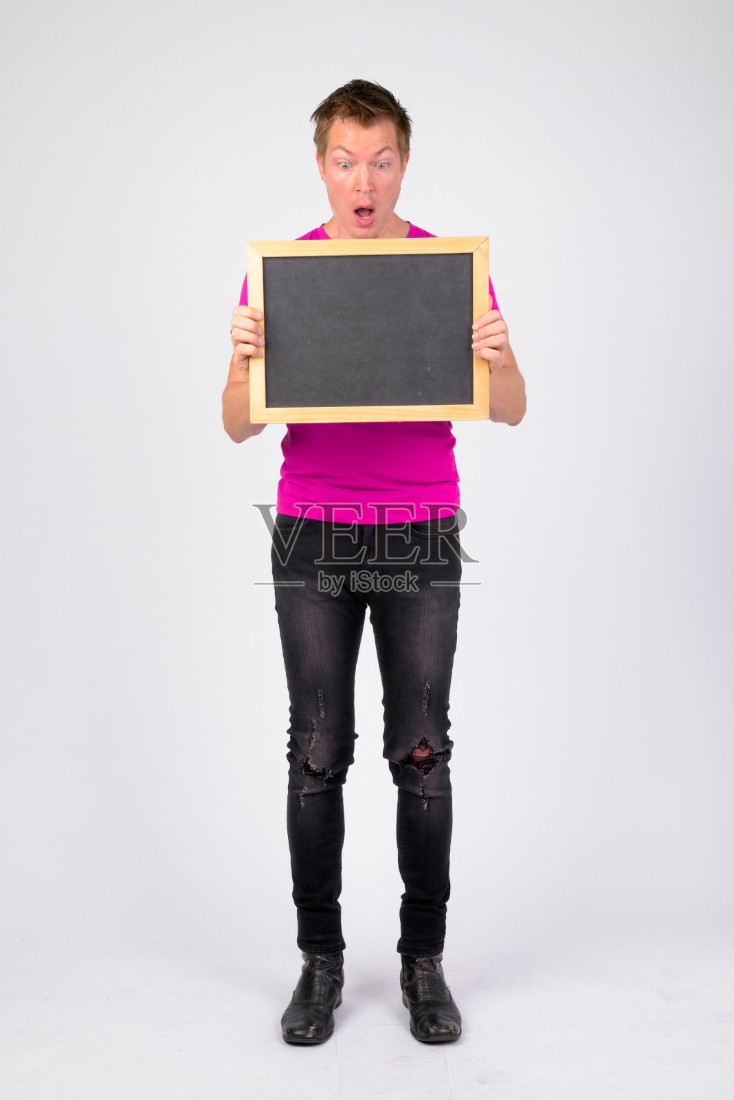 在展示黑板时，年轻英俊的男子看起来很震惊照片摄影图片