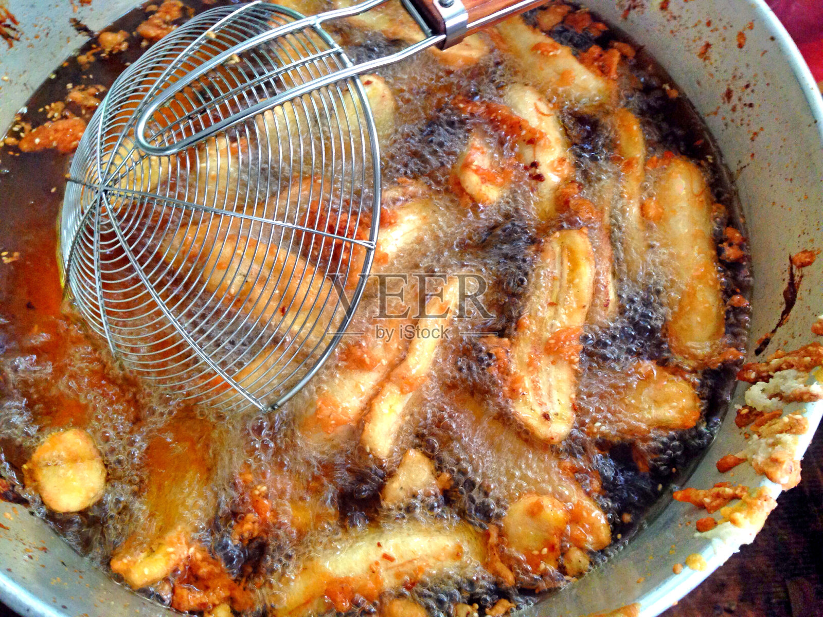 香蕉被切成片，然后用热油炸。用热油在平底锅里炸香蕉。油炸香蕉片。照片摄影图片