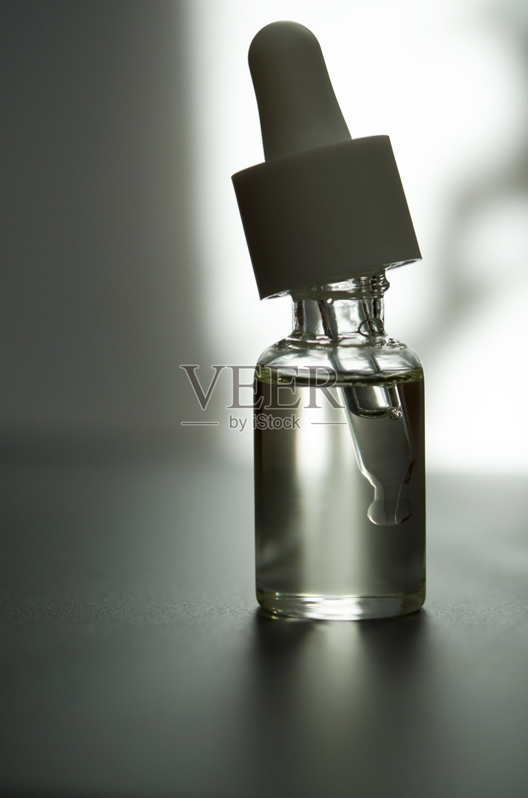 化妆或医疗用的带吸管的玻璃瓶。皮肤护理的概念。自然光硬，阴影深。——图片照片摄影图片