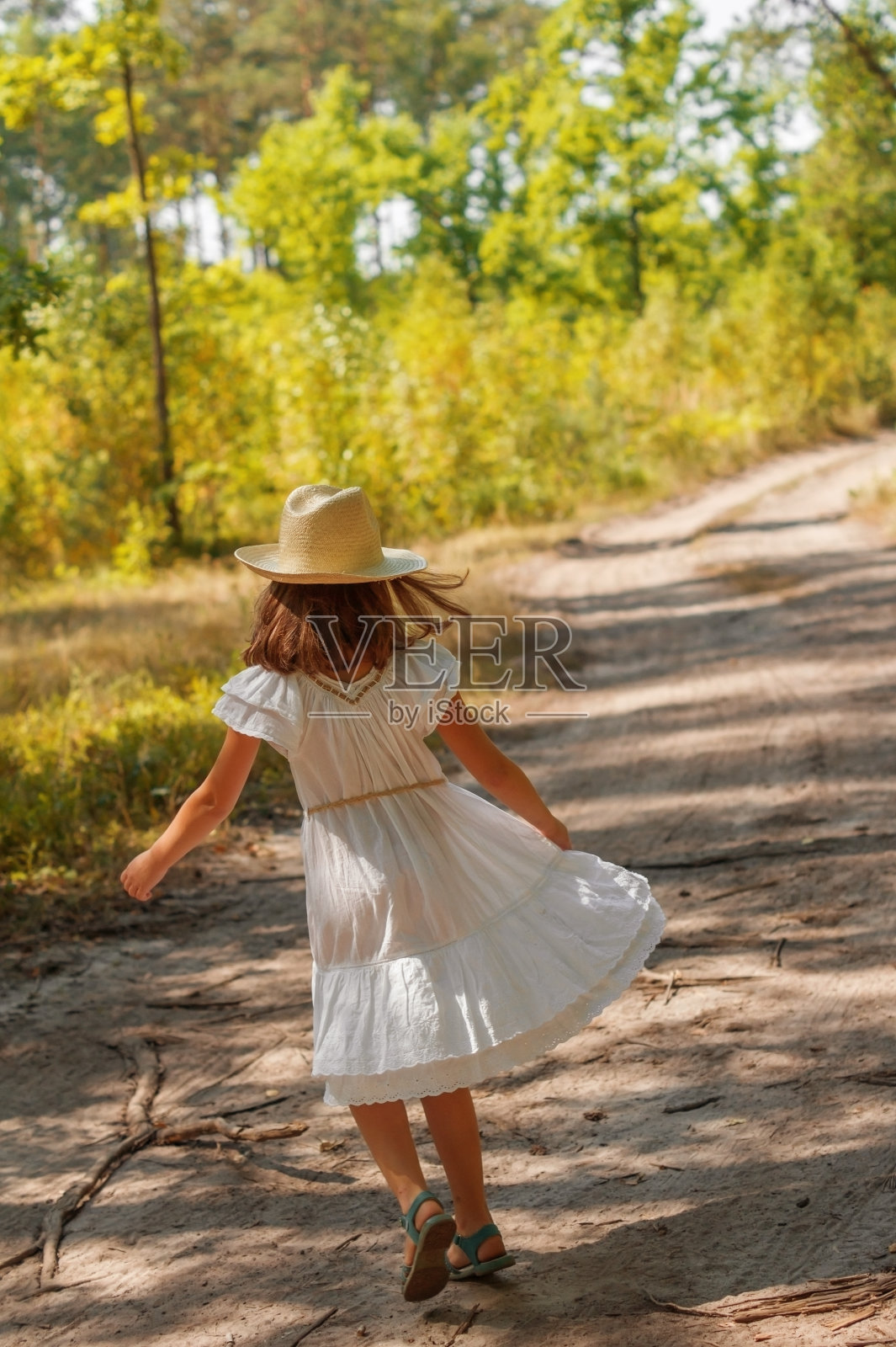 穿着白色连衣裙的小女孩在夏日的森林里跳舞照片摄影图片