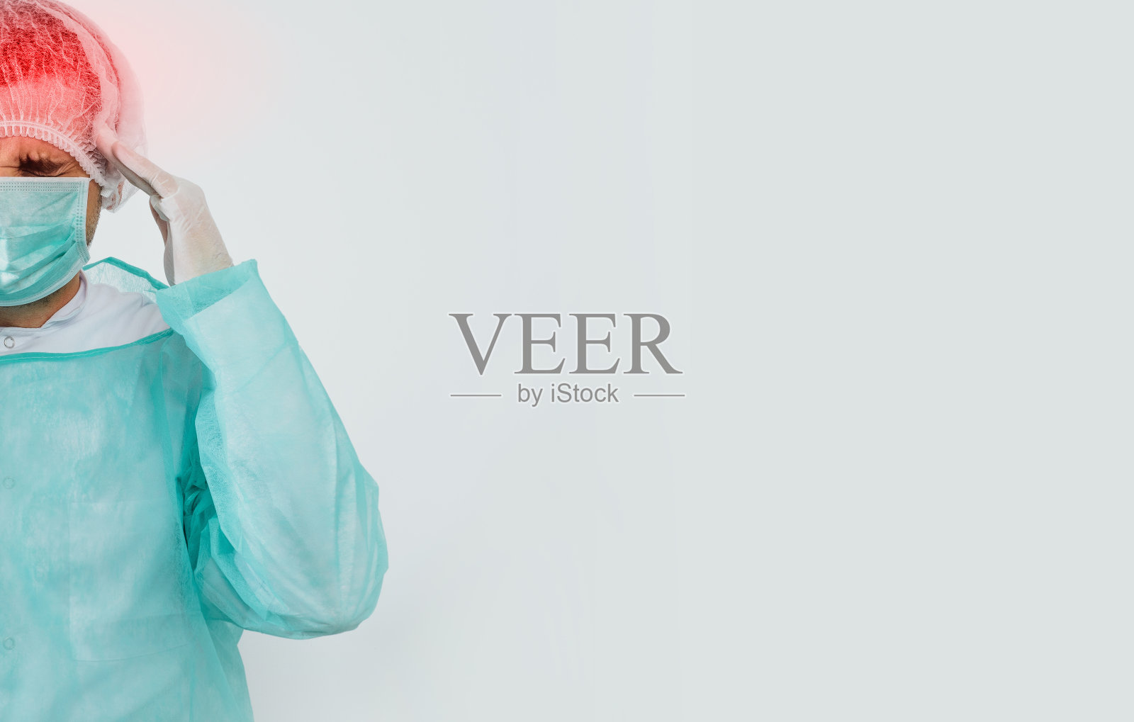 外科医生头痛，医生。一名男子穿着绿色手术围裙，在明亮的背景下戴着口罩，正抱着头照片摄影图片