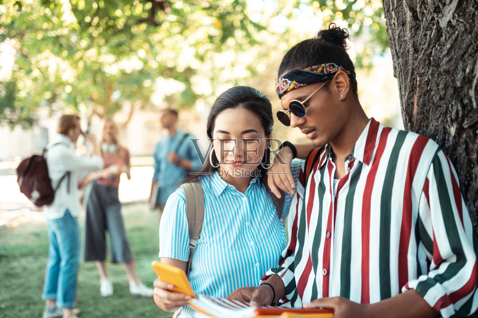 一对情侣站在大学朋友面前。照片摄影图片