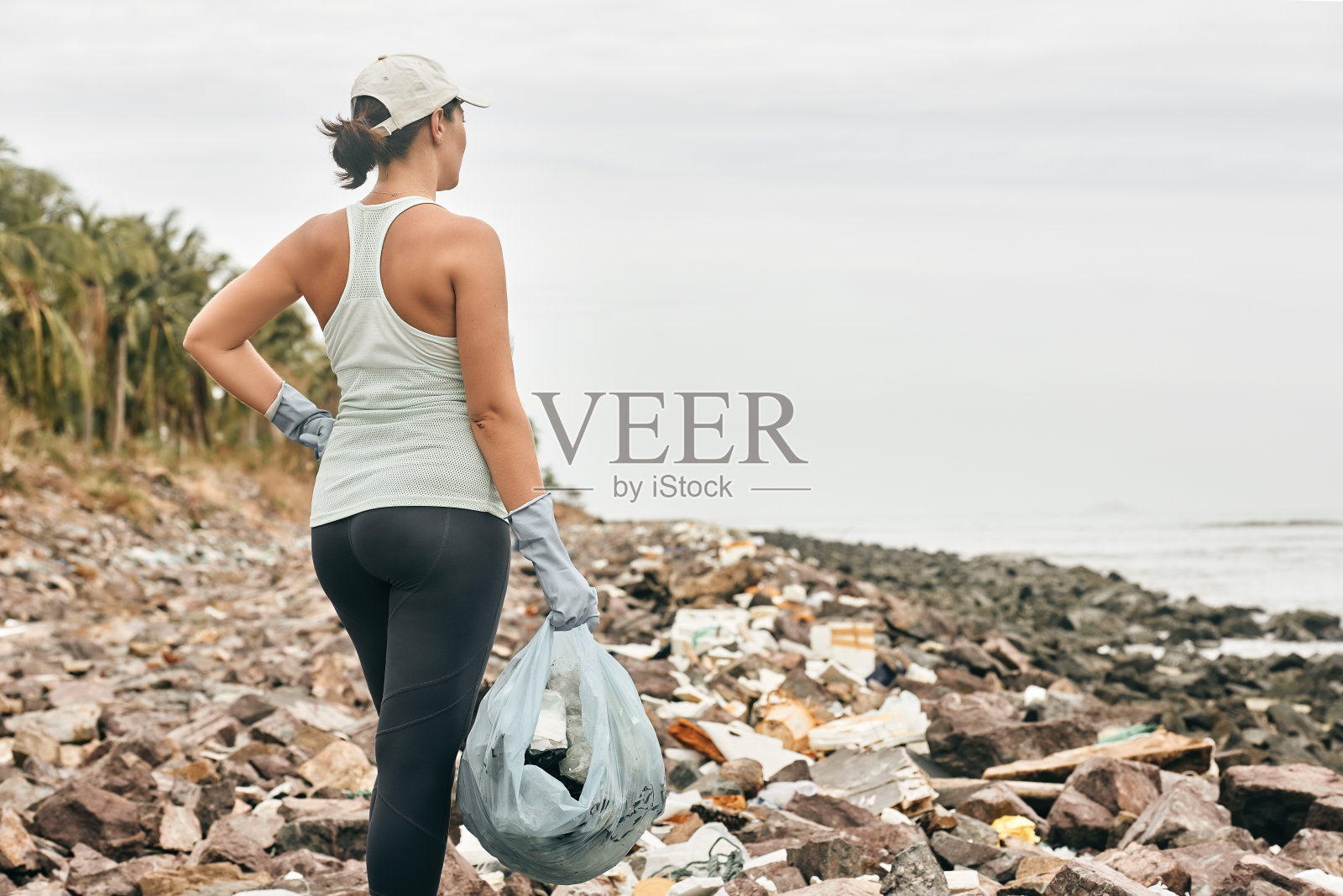 女志愿者戴着手套在海岸背景下拿着塑料垃圾照片摄影图片