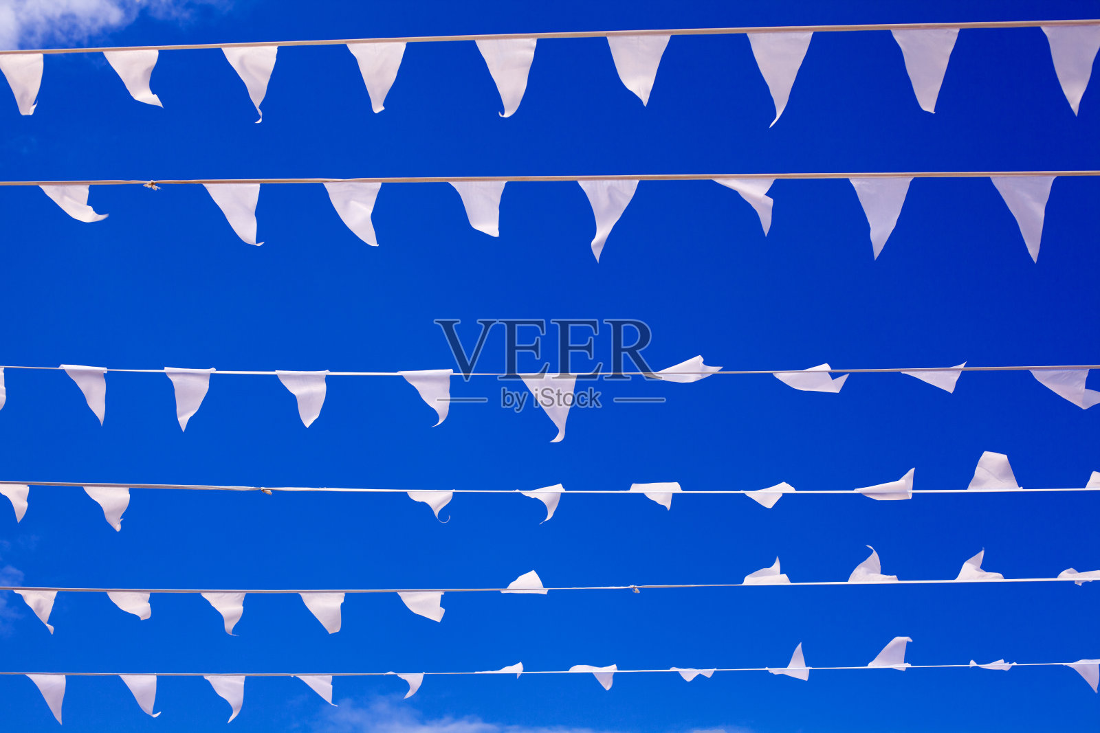 白旗迎风飘扬在深蓝色的天空背景近处，彩旗迎风飘扬，装饰花环在空中飘动，美丽的彩旗线条飘动，三角形的彩旗在蔚蓝的天空中飘扬照片摄影图片