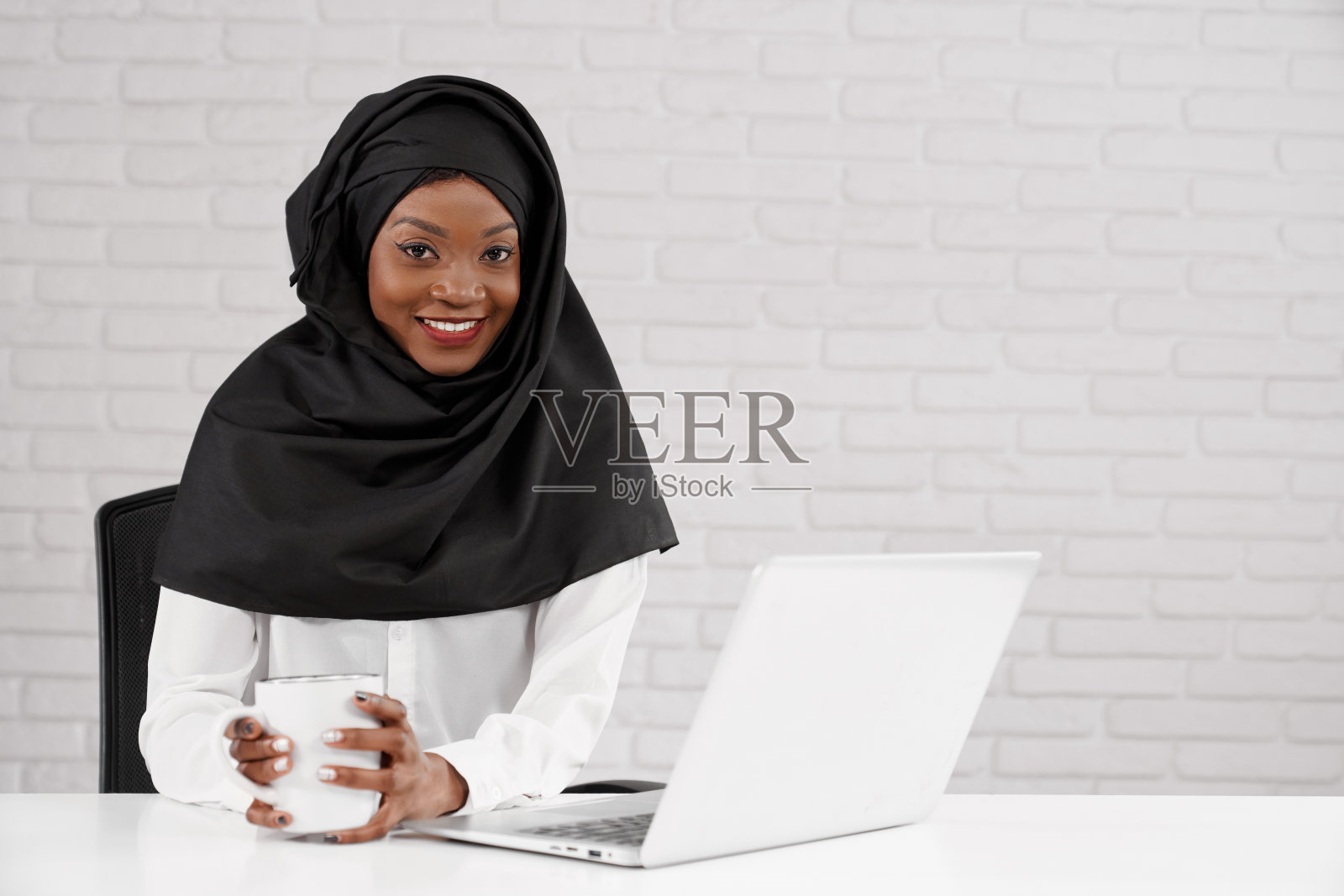 非洲女办公室工作人员在黑色头巾的姿势。照片摄影图片