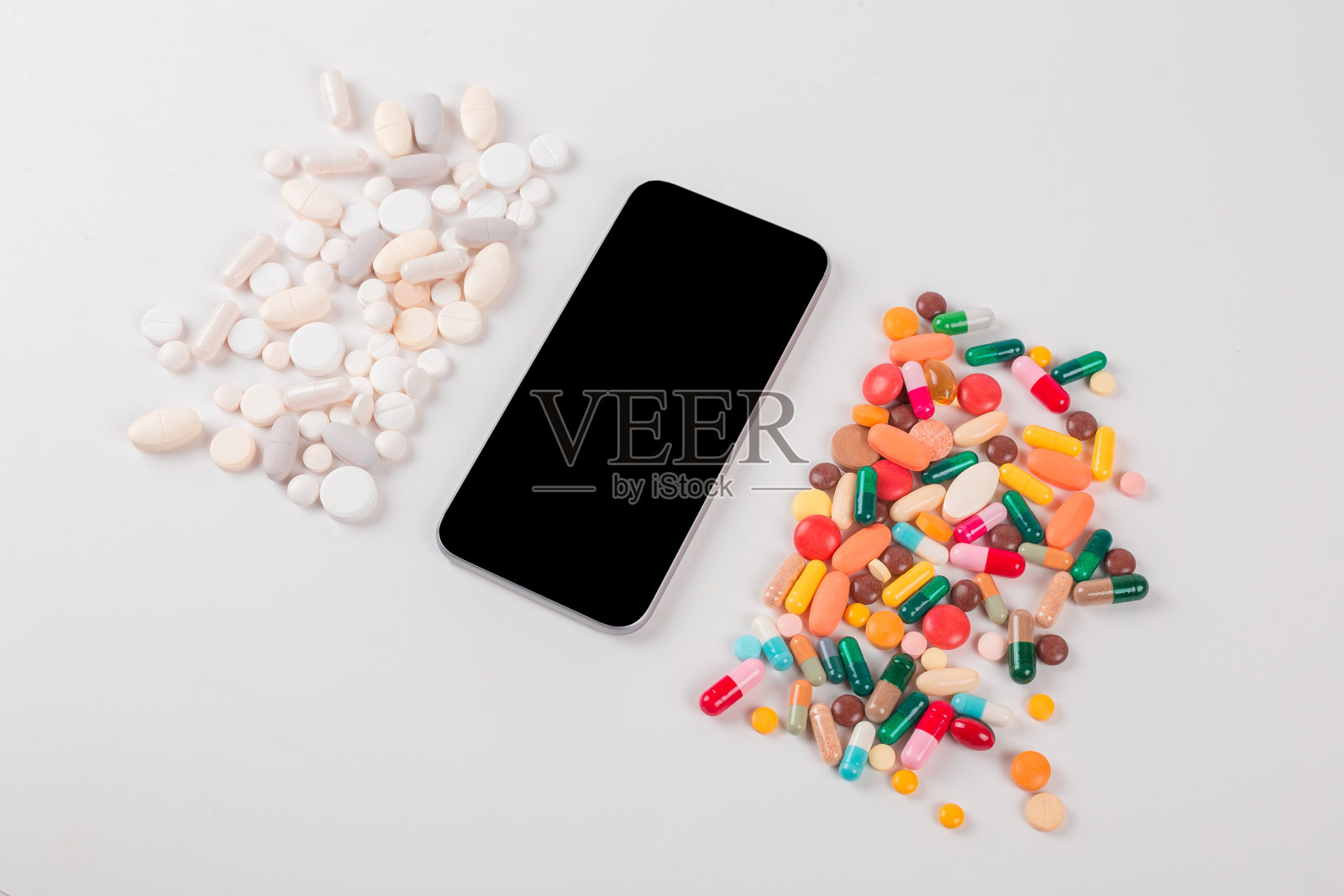 大量药丸和手机在白色的背景表面。制药行业的高分辨率图像。手机应用程序照片摄影图片