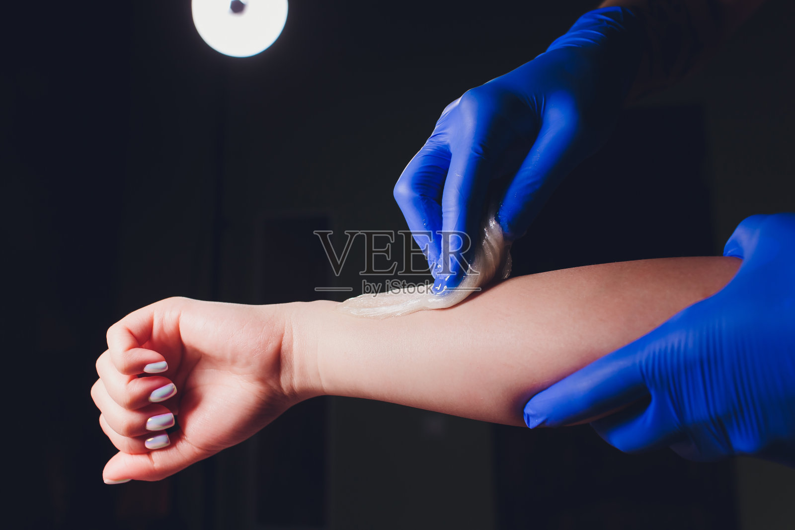 糖渍。美丽的概念。年轻漂亮的黑发女孩得到了去除头发的程序液体糖。脱毛和美容概念-程序的头发去除手上对美丽的女人。照片摄影图片