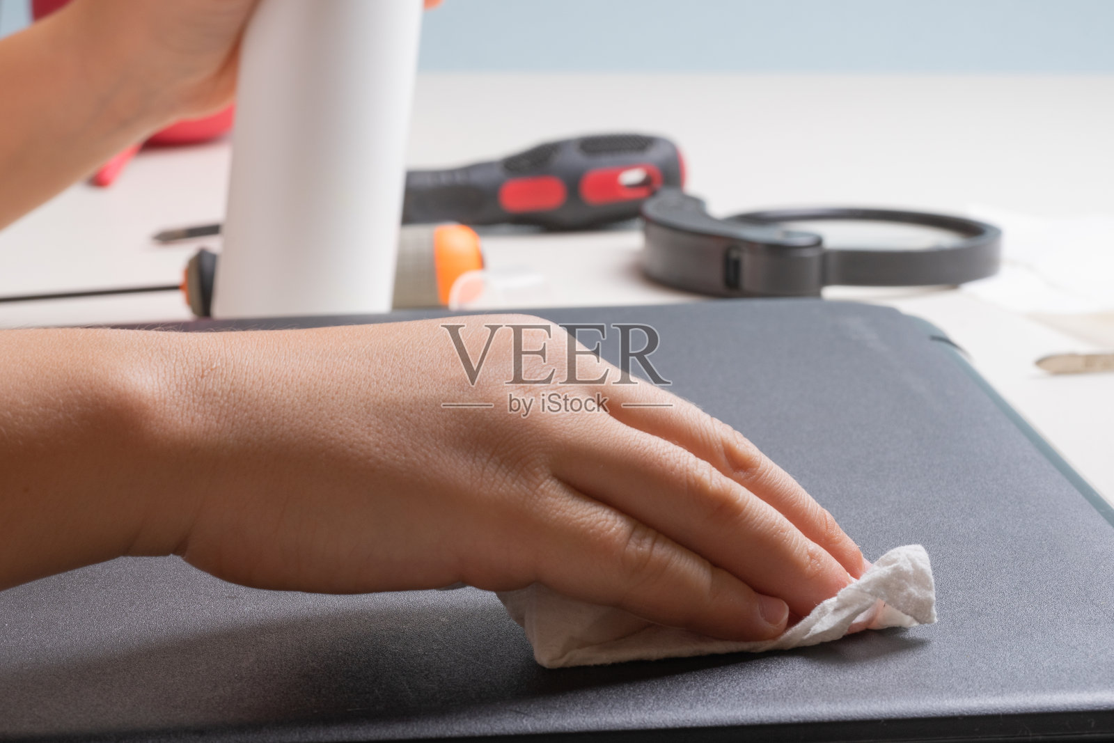 一个10岁的男孩正在用一种特殊的布和清洁剂清洁他的笔记本电脑。照片摄影图片