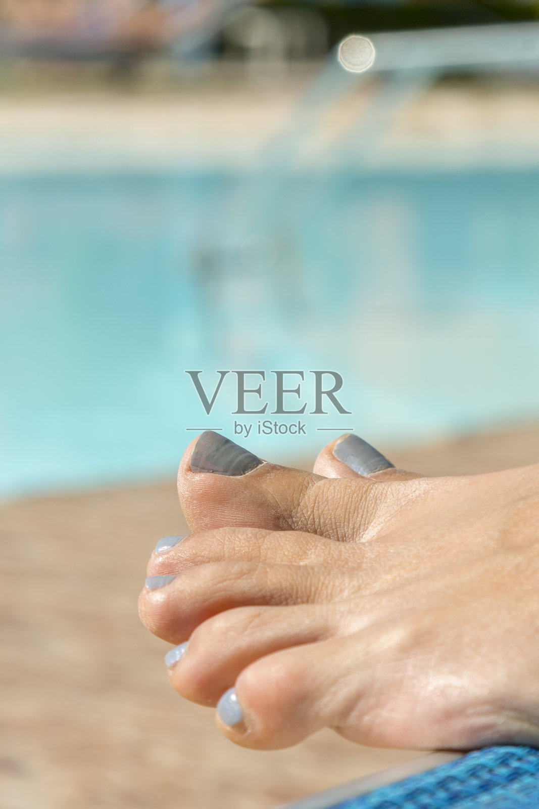 女孩们的腿在泳池边。在游泳池里放松。女人的脚抵着游泳池休息。垂直图照片摄影图片