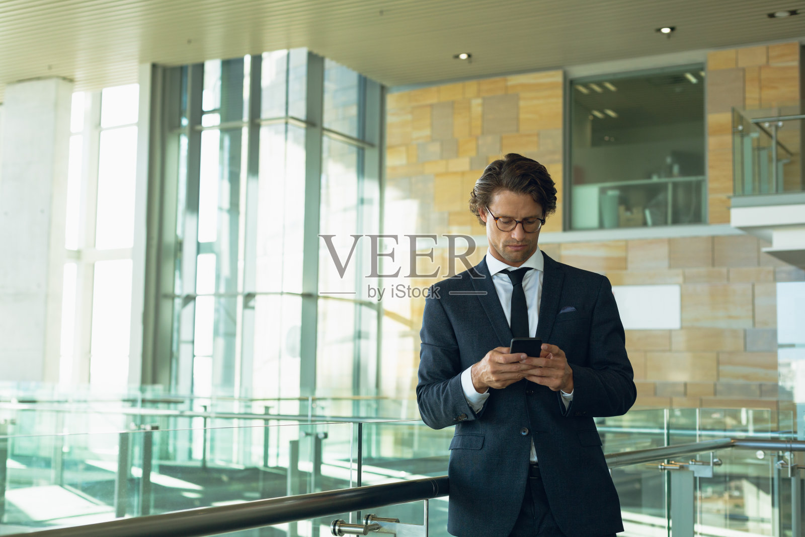 商人在现代办公大楼的栏杆附近使用手机照片摄影图片