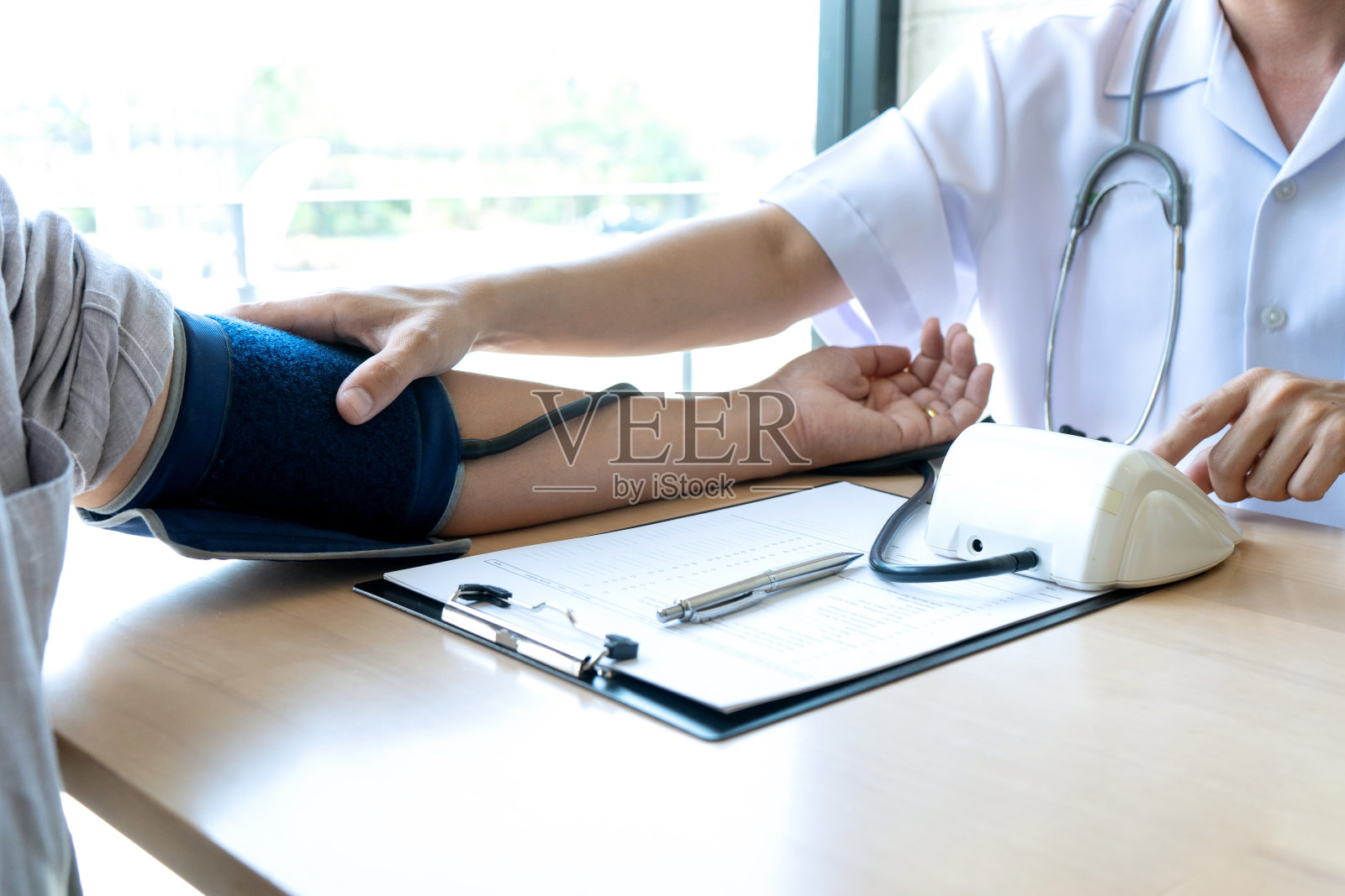 医生坐测试压力表和检查病人照片摄影图片