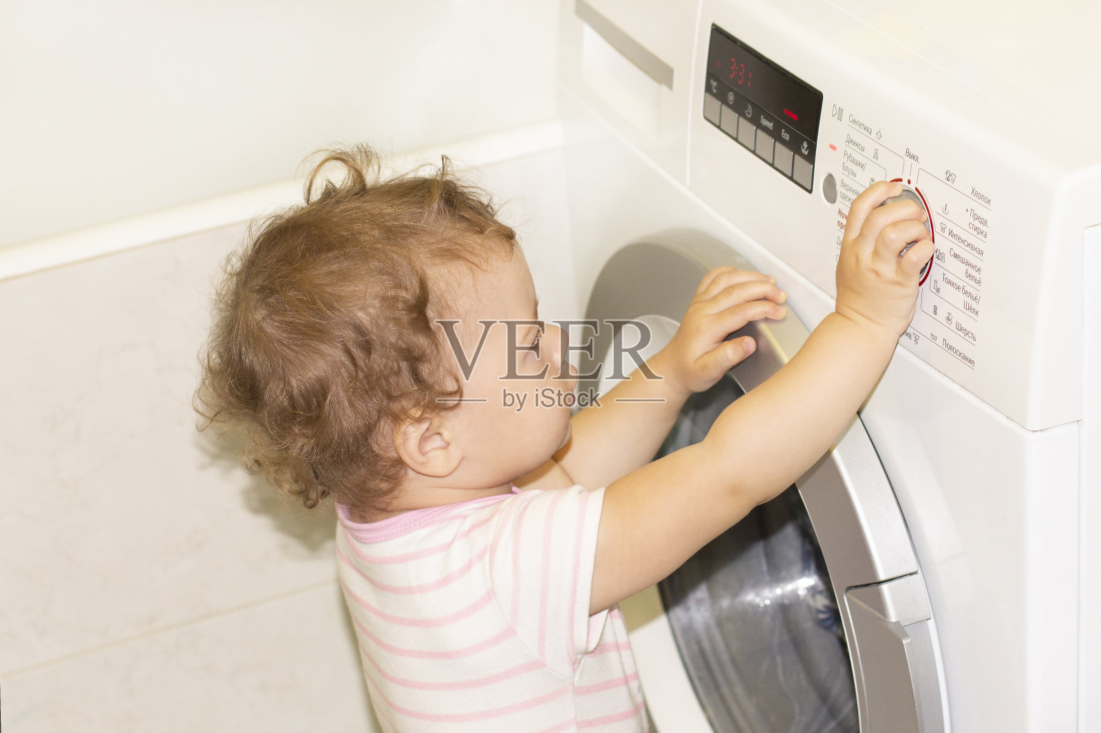 小女婴按下了洗衣机上的按钮照片摄影图片