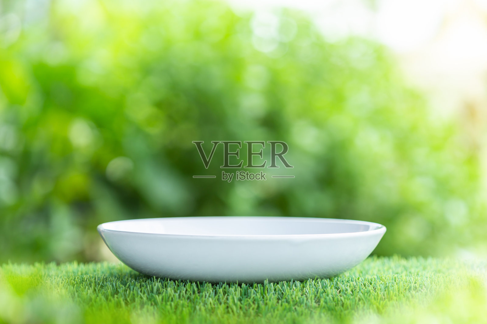 木桌上白色的陶瓷空盘，绿色模糊的灯光背景。的照片蒙太奇照片摄影图片