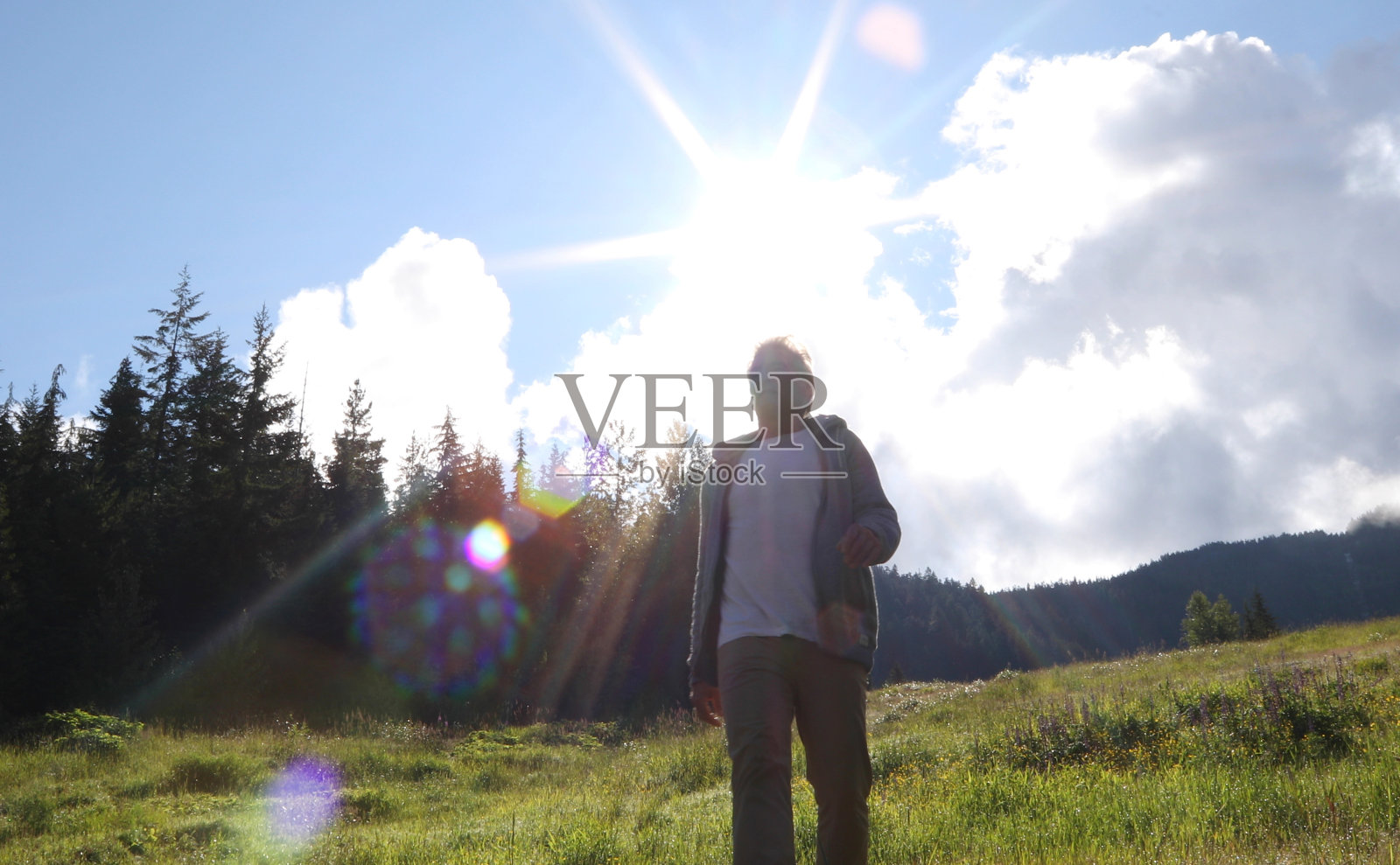 晨曦中，人们走过山间草地照片摄影图片