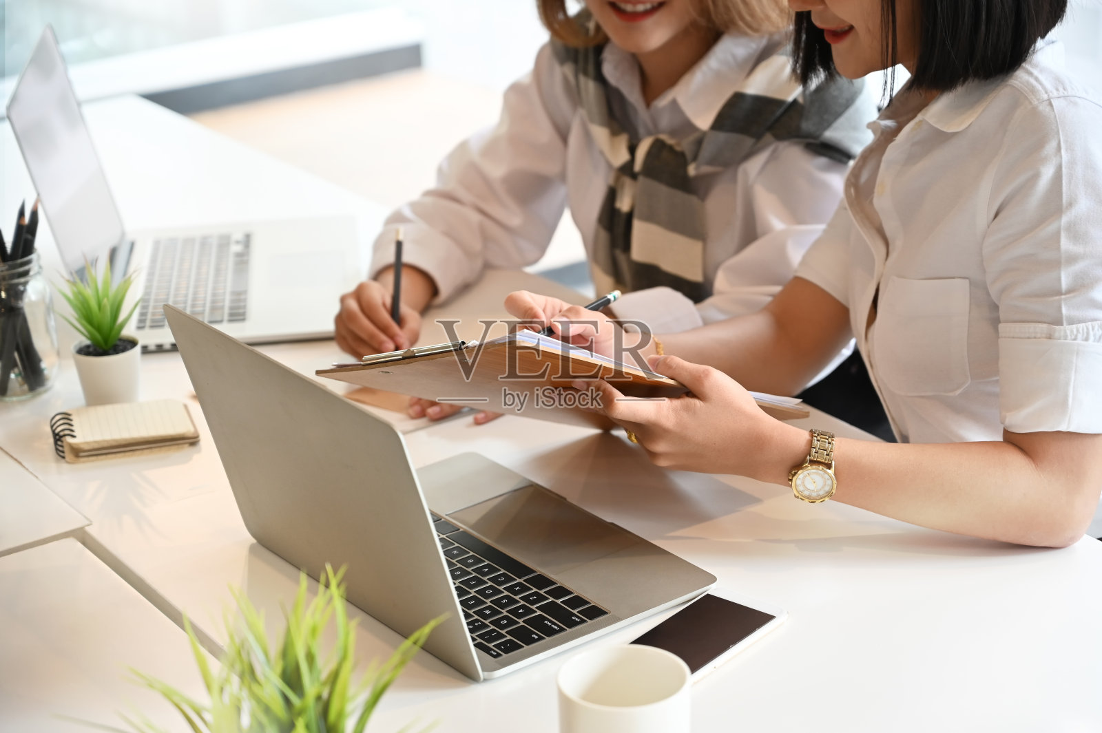 两个年轻的女人在工作台上与创业项目会面。照片摄影图片