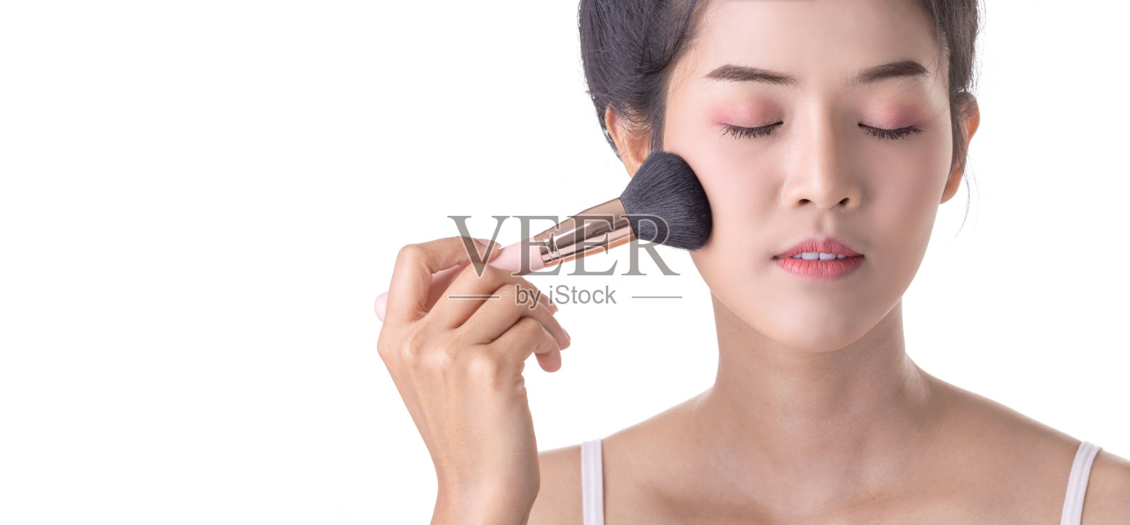 美丽的年轻亚洲女人使用软刷和化妆品在自己的脸上。美容师，皮肤护理或美容概念照片摄影图片