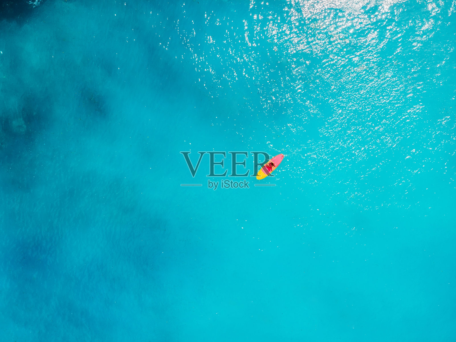 鸟瞰图上的女人站起来划桨板在蓝色的海洋。照片摄影图片