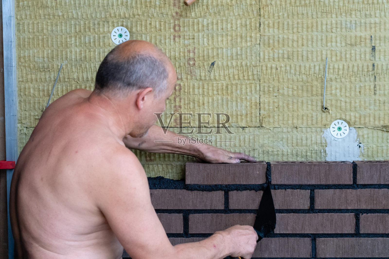 在建筑工地上安装砖块的砌砖工人。照片摄影图片