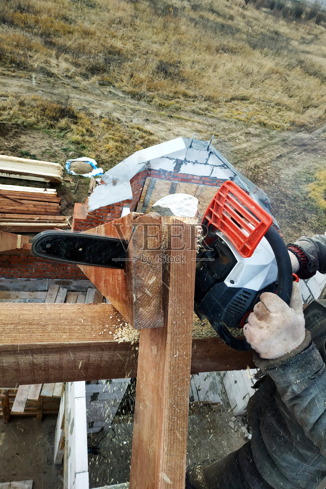 建筑工人在屋顶上用链锯锯木头。屋顶椽子照片摄影图片