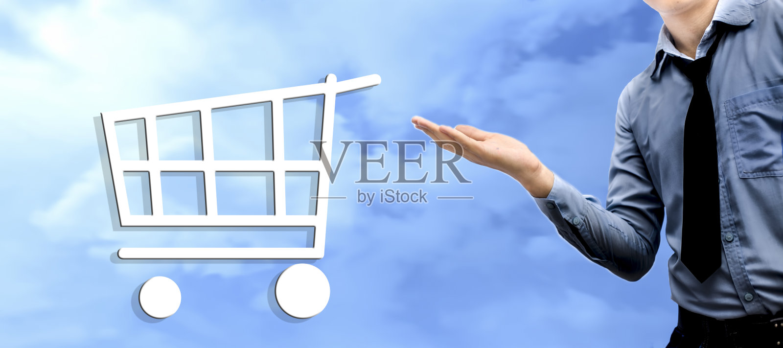 一个穿着蓝色衬衫，打着黑色领带，手里拿着什么东西，没有主题的年轻商人。孤立在蓝色的天空背景。用一个手推车图标，营销的概念。照片摄影图片