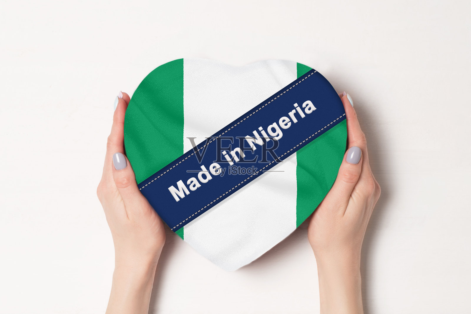 尼日利亚国旗上的铭文。女人的手拿着一个心形的盒子。白色背景。照片摄影图片