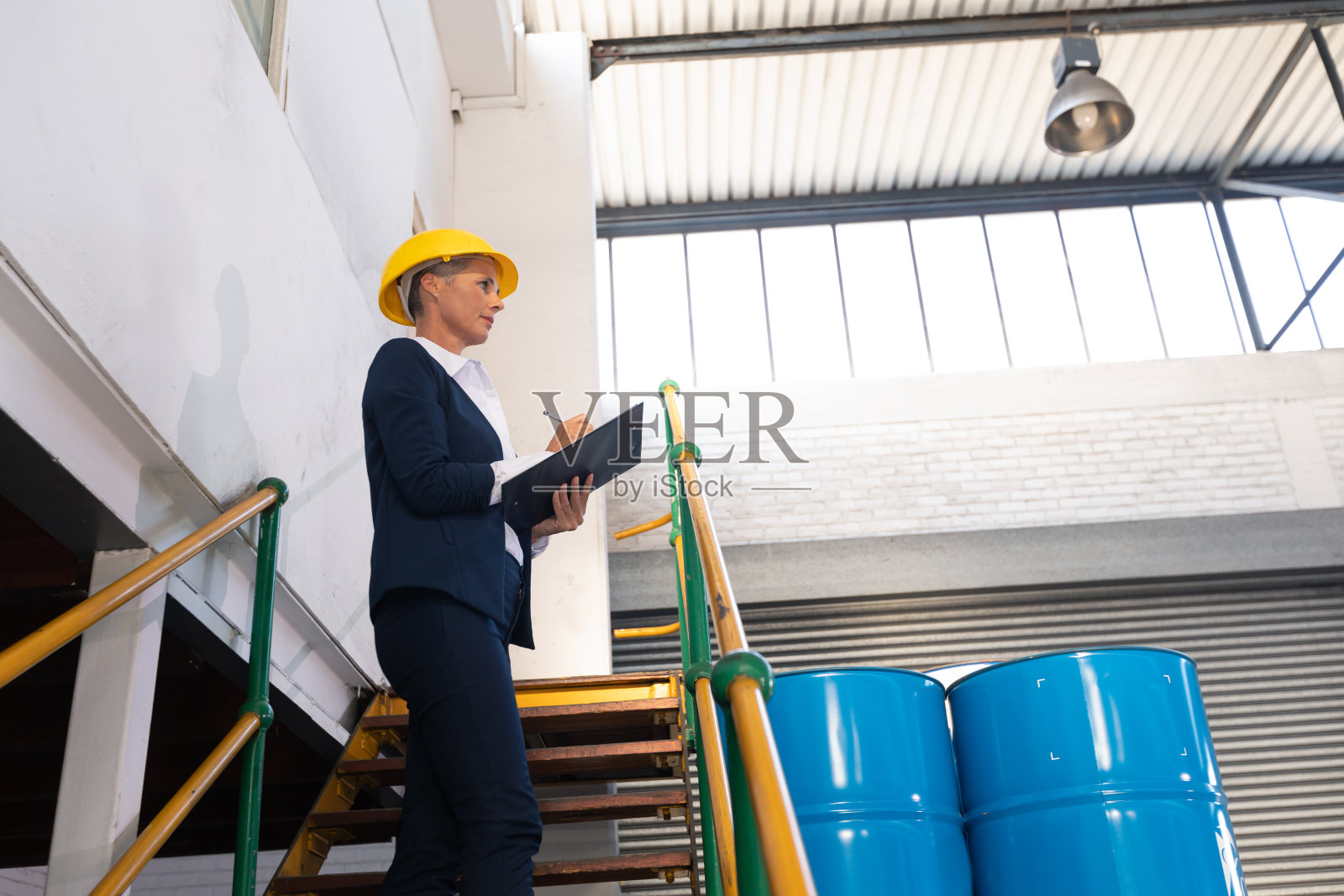 女经理在仓库楼梯的写字板上写字照片摄影图片