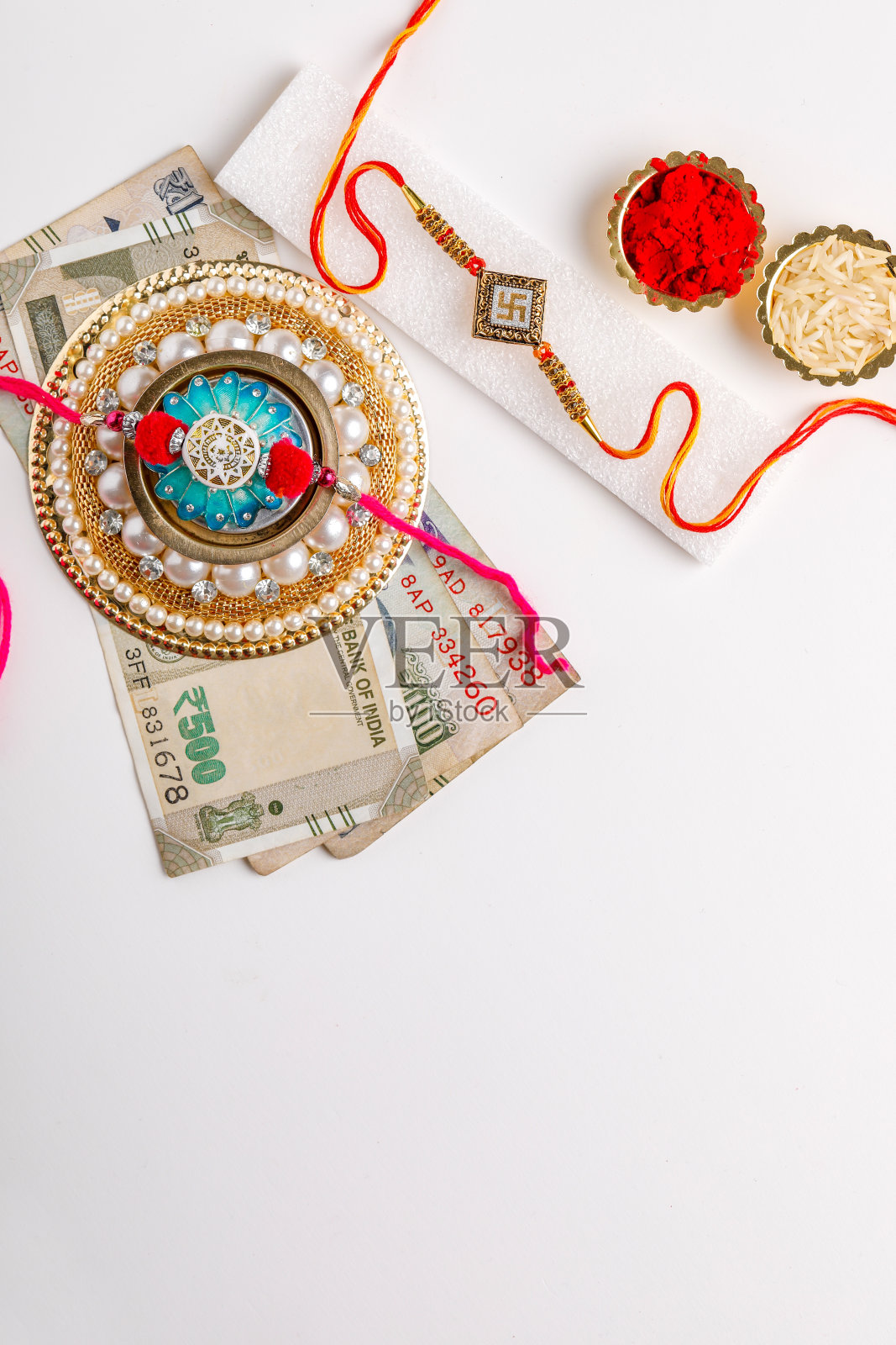 印度节日Raksha Bandhan，优雅的Rakhi大米，kumkum与印度货币在白色的背景照片摄影图片