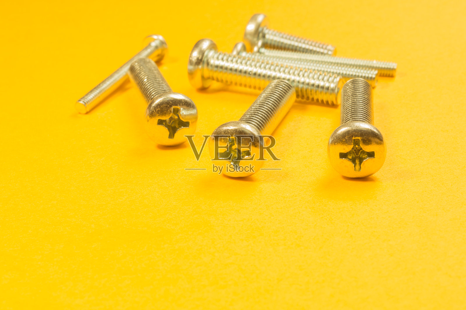黄色背景上的钢螺钉照片摄影图片