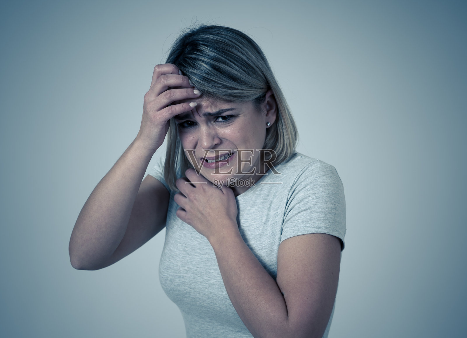 近距离的肖像年轻女子感到害怕和震惊隐藏她的脸从可怕的东西。带着恐惧的眼神看着她。人与人的表达和情感的概念。喜怒无常的光。照片摄影图片