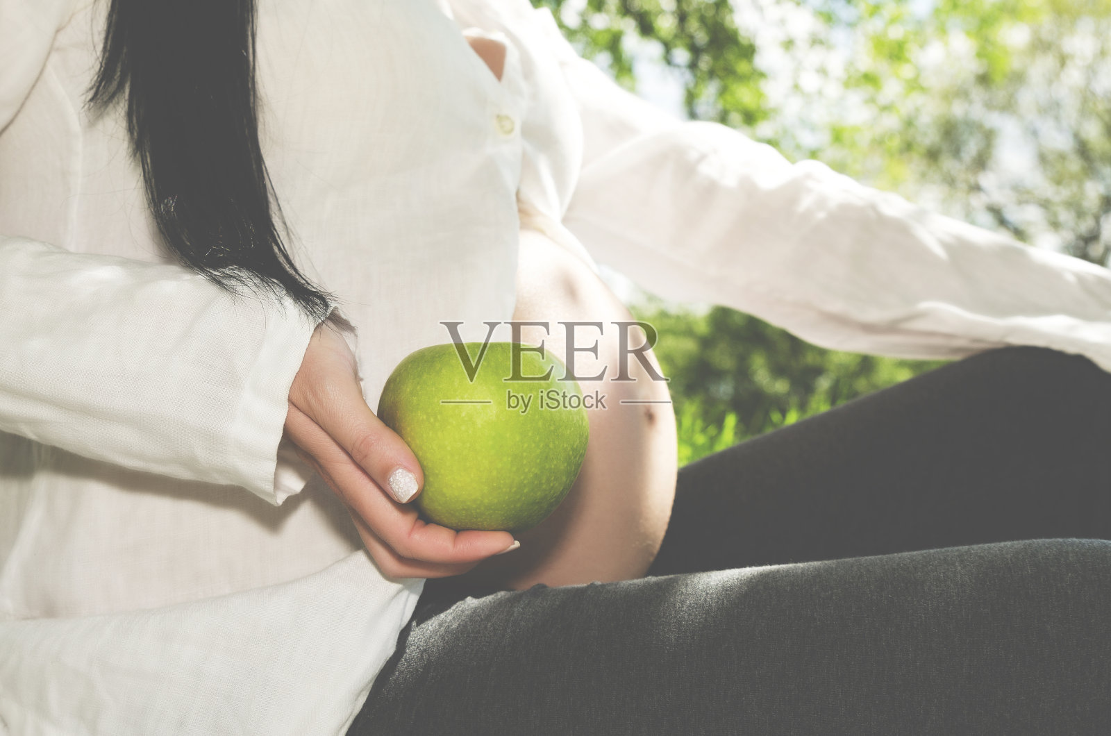 身体部位孕肚和手握青苹果选择性聚焦照片摄影图片