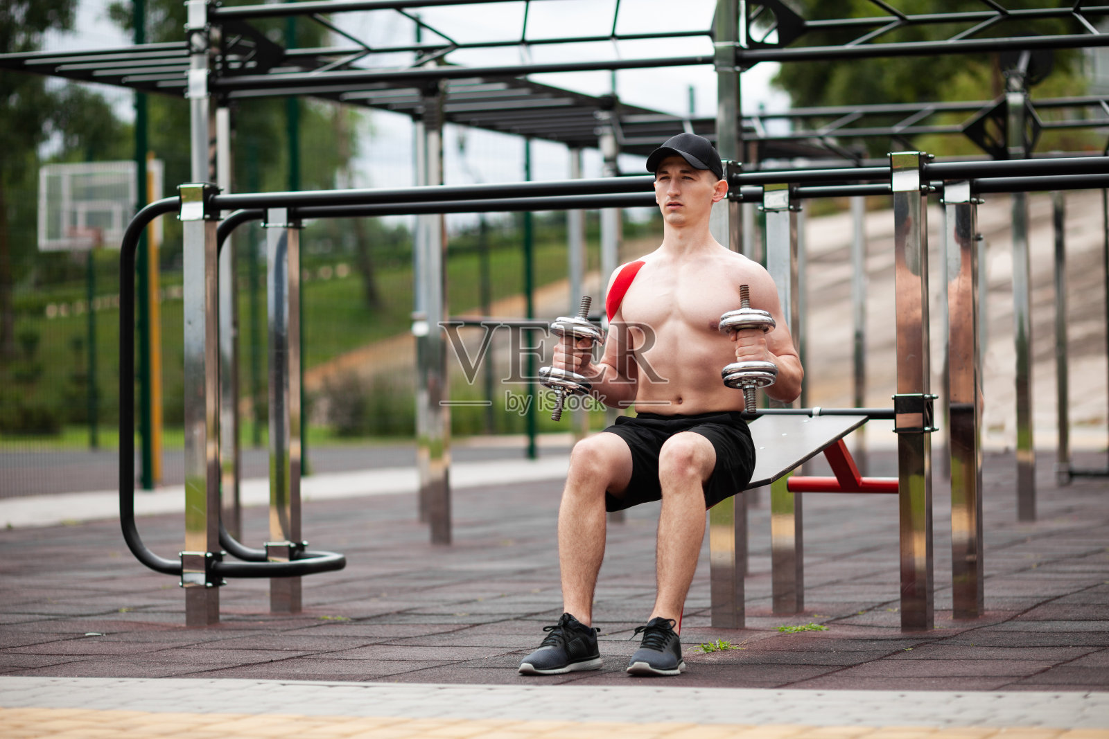 受伤的欧洲年轻运动员正在户外训练。肩部运动机能学(治疗，Kinesio, k-tape, KT, physio)胶带。康复和恢复。运动与哑铃照片摄影图片