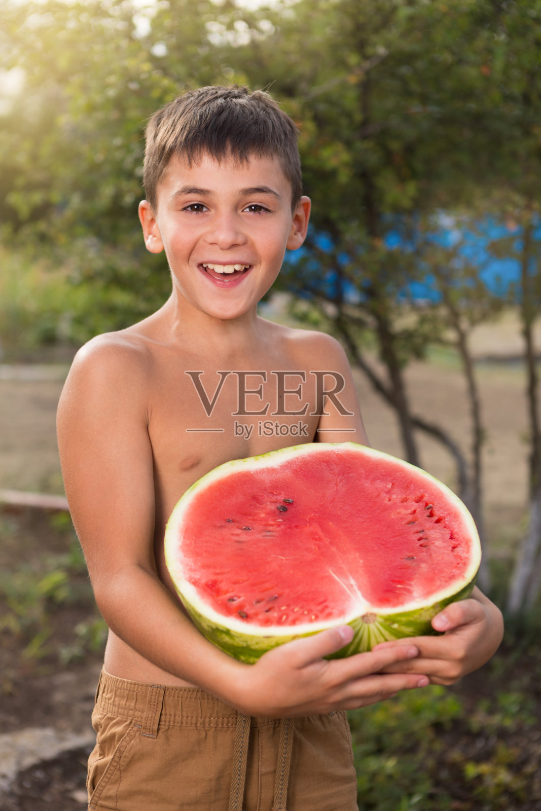 快乐的男孩拿着切好的西瓜笑，夏天的概念，红熟的西瓜照片摄影图片