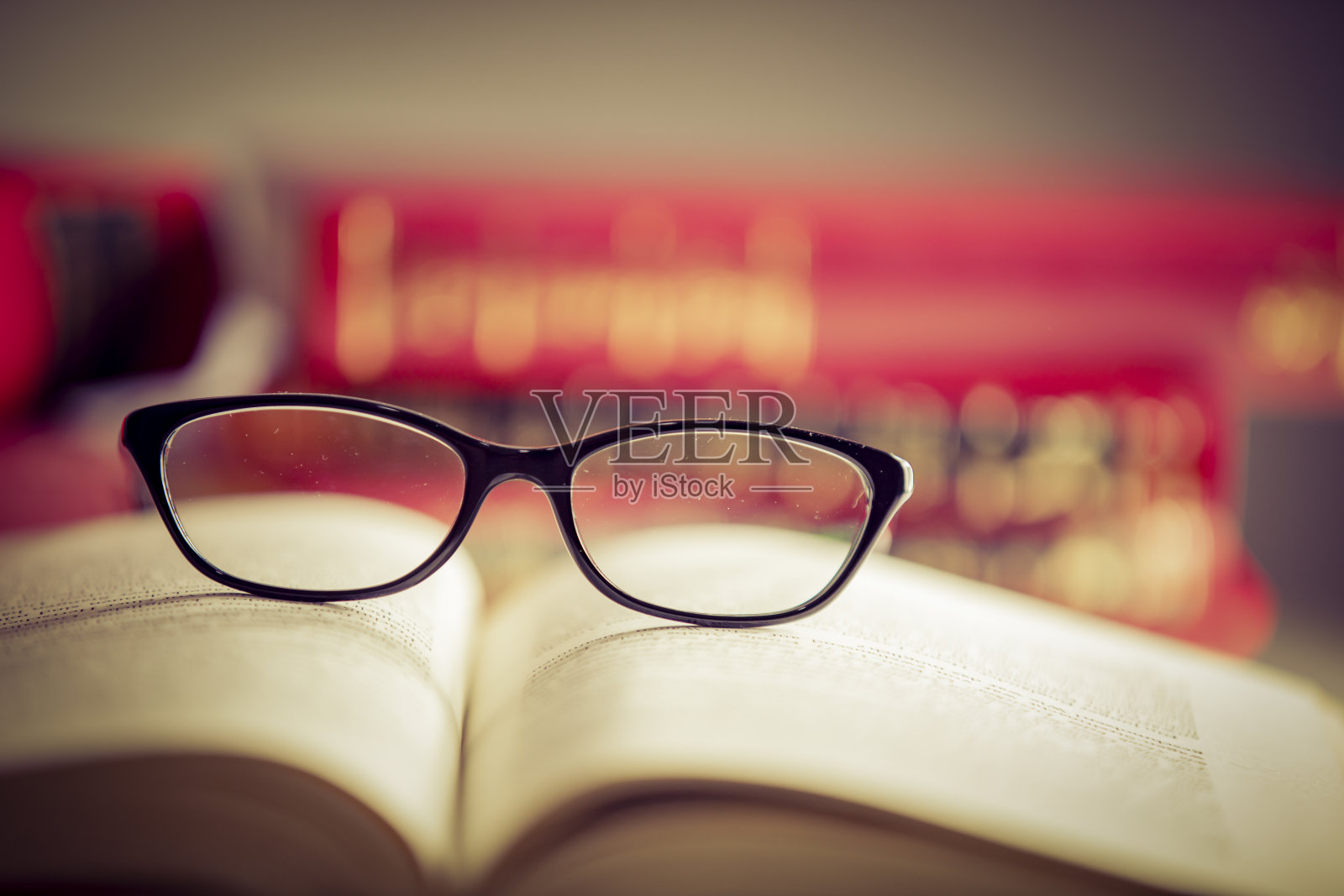 眼镜躺在红色的书上照片摄影图片