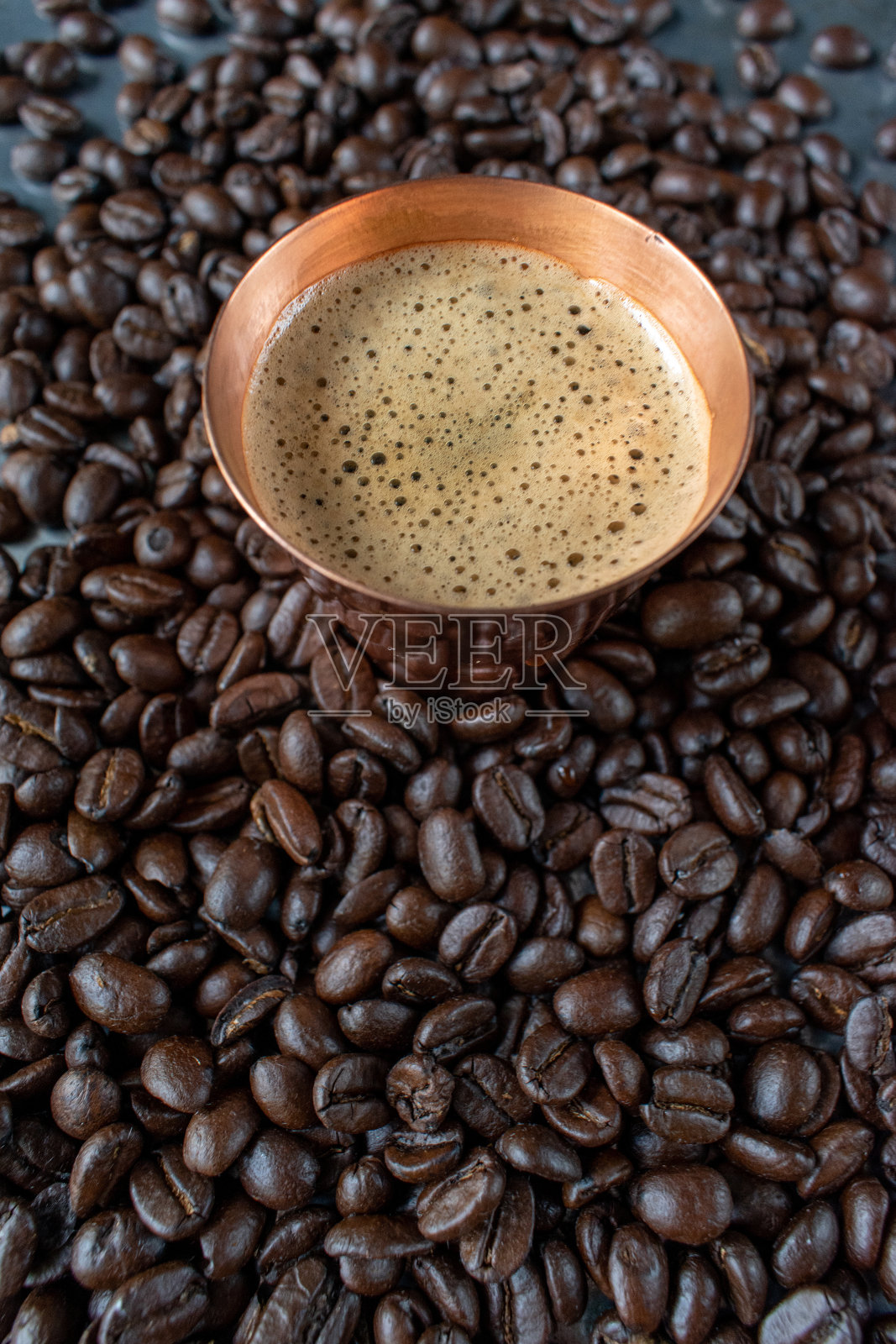 质朴的桌子上摆放着生咖啡豆，铜杯里盛满了意式浓缩咖啡照片摄影图片