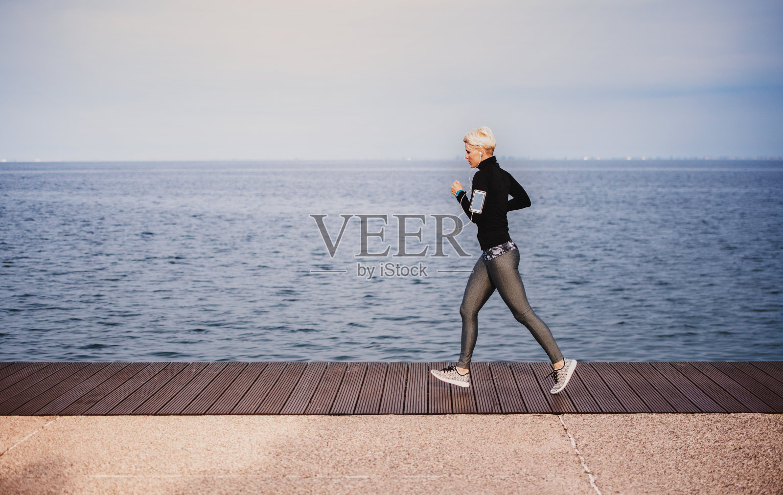 年轻的女运动员在沙滩上跑步的侧视图。照片摄影图片