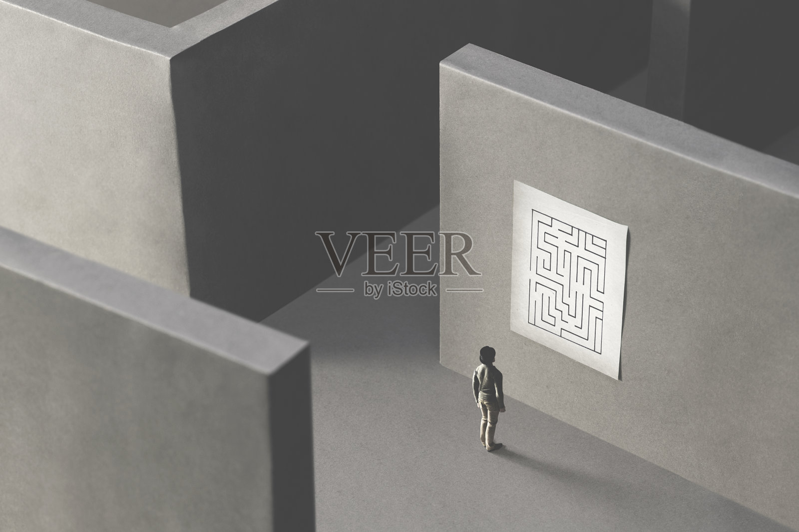 人迷失在复杂的迷宫中，观察地图来寻找出路;超现实主义的概念照片摄影图片