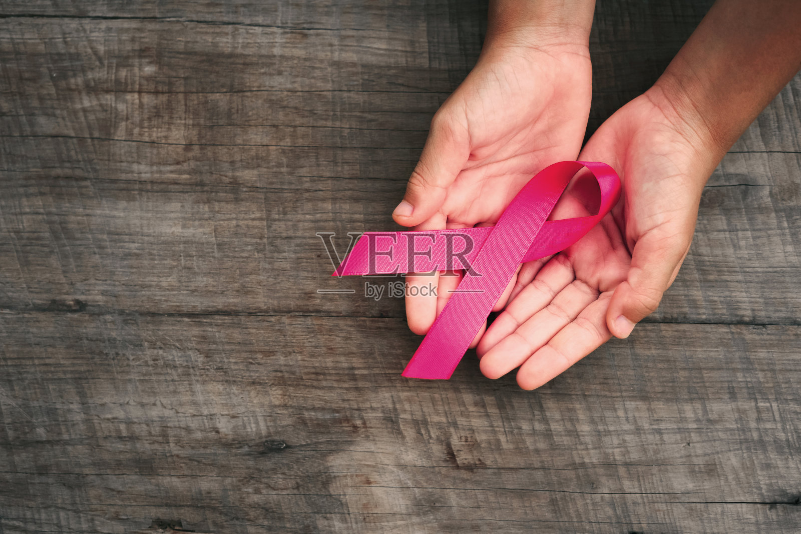 概念医疗保健和医学。手拿粉红丝带在木头上。乳腺癌意识。希望的迹象照片摄影图片