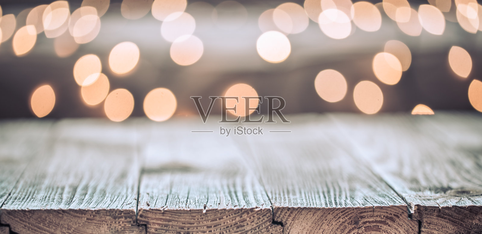 圣诞假日背景用空的木质桌面盖上节日的散景灯装饰。照片摄影图片