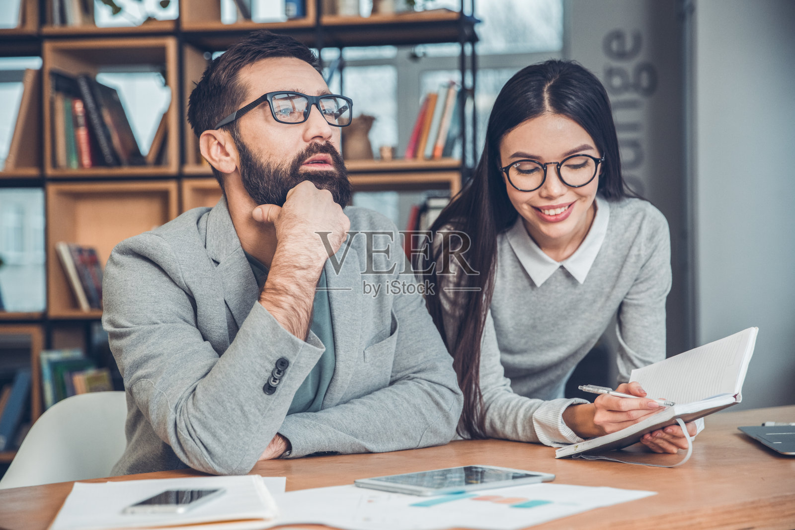 在办公室里一起工作的创业者，老板坐在那里沉思着，而秘书愉快地记录着他的想法照片摄影图片