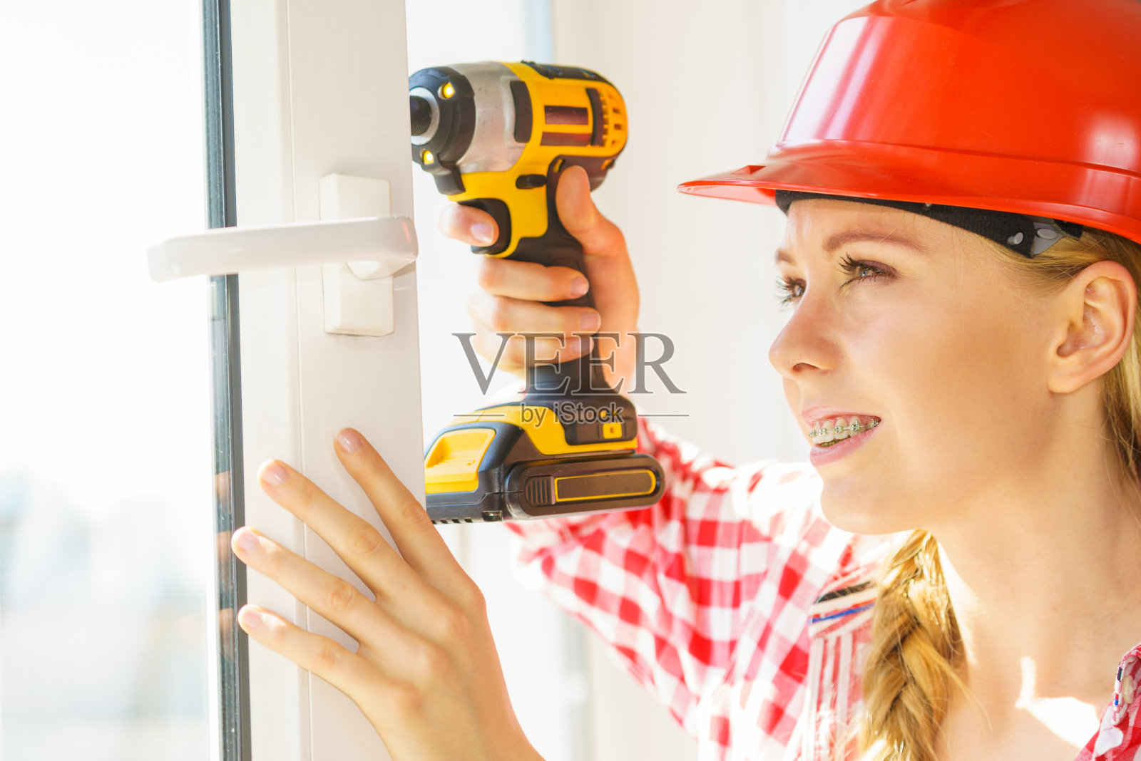 妇女用钻固定或安装窗户照片摄影图片
