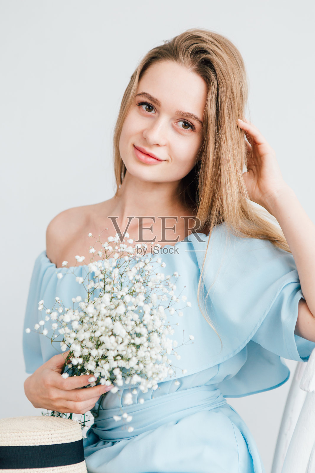 女孩长头发和帽子摆姿势与一束白花照片摄影图片