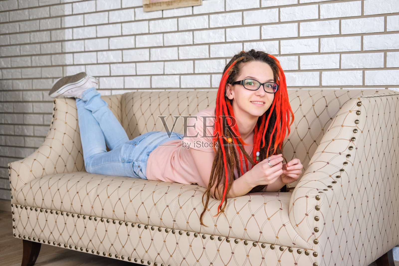 梳着红辫的女孩坐在明亮的房间里。照片摄影图片