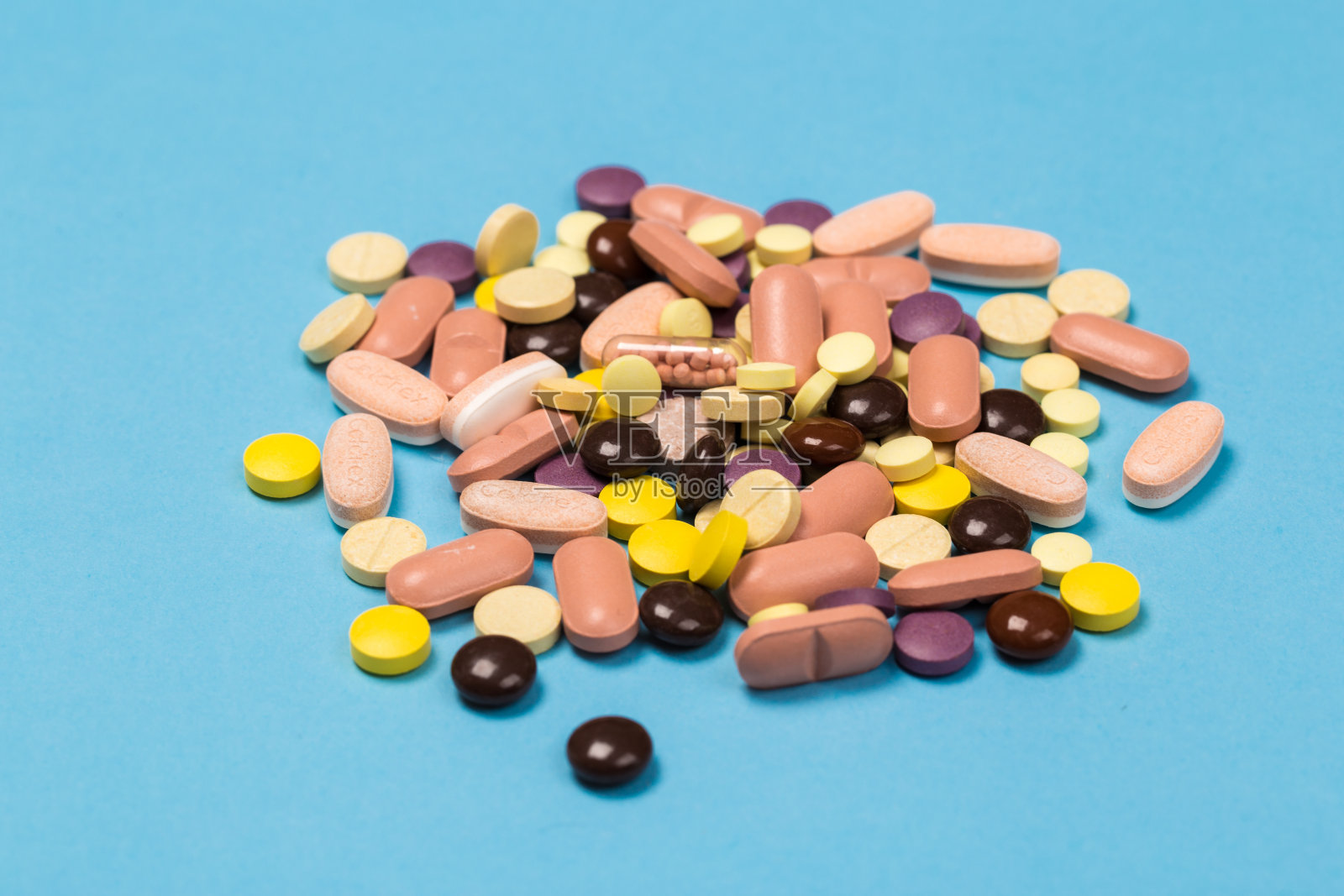 蓝色的背景上散落着许多五颜六色的药丸。药片散布在蓝色的背景上。关闭了。医学背景。照片摄影图片
