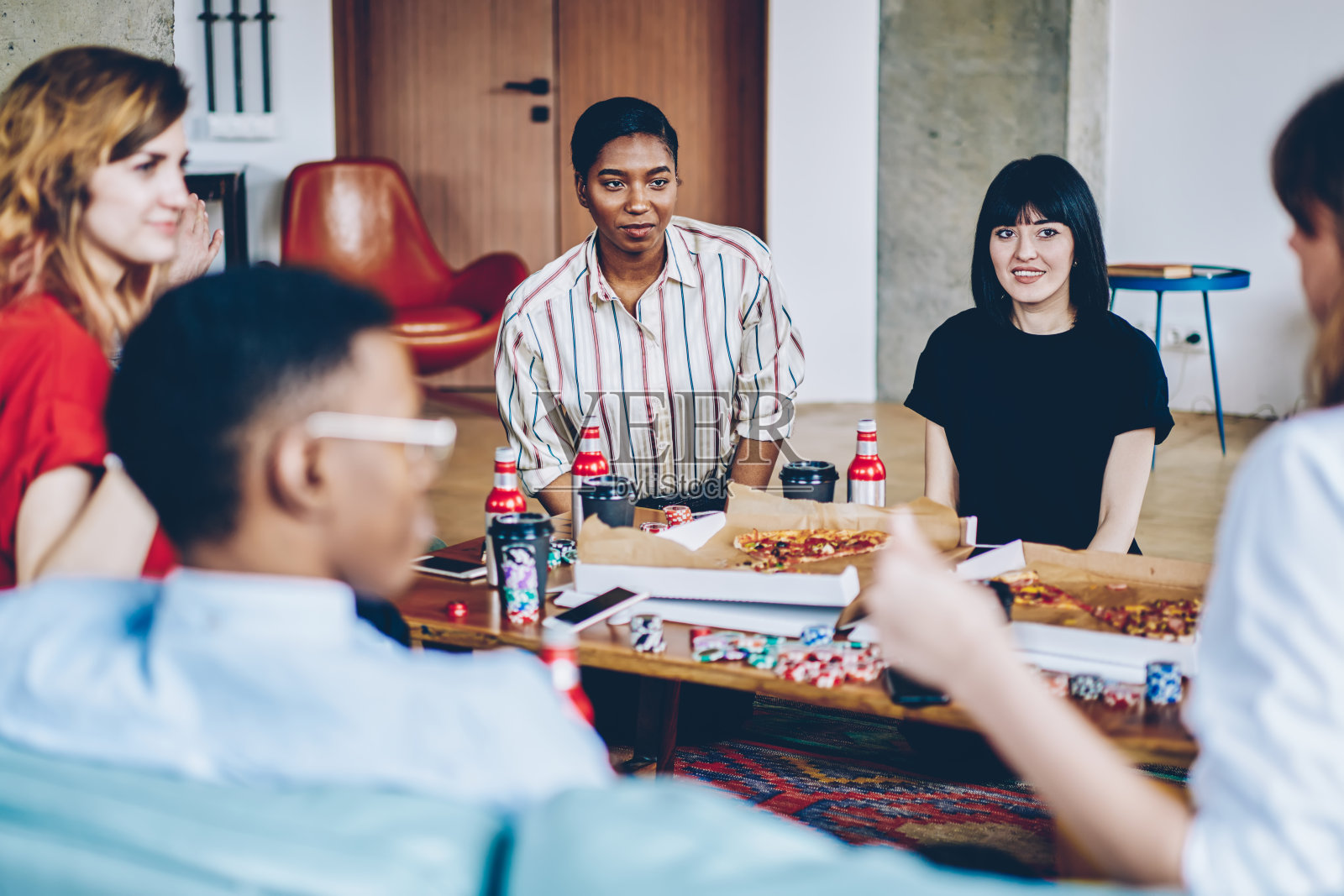 各式各样的年轻人穿着休闲装，在公寓的轰趴中消磨闲暇时间赌博。来自不同文化的潮人朋友们在公寓里互相交流和休息照片摄影图片