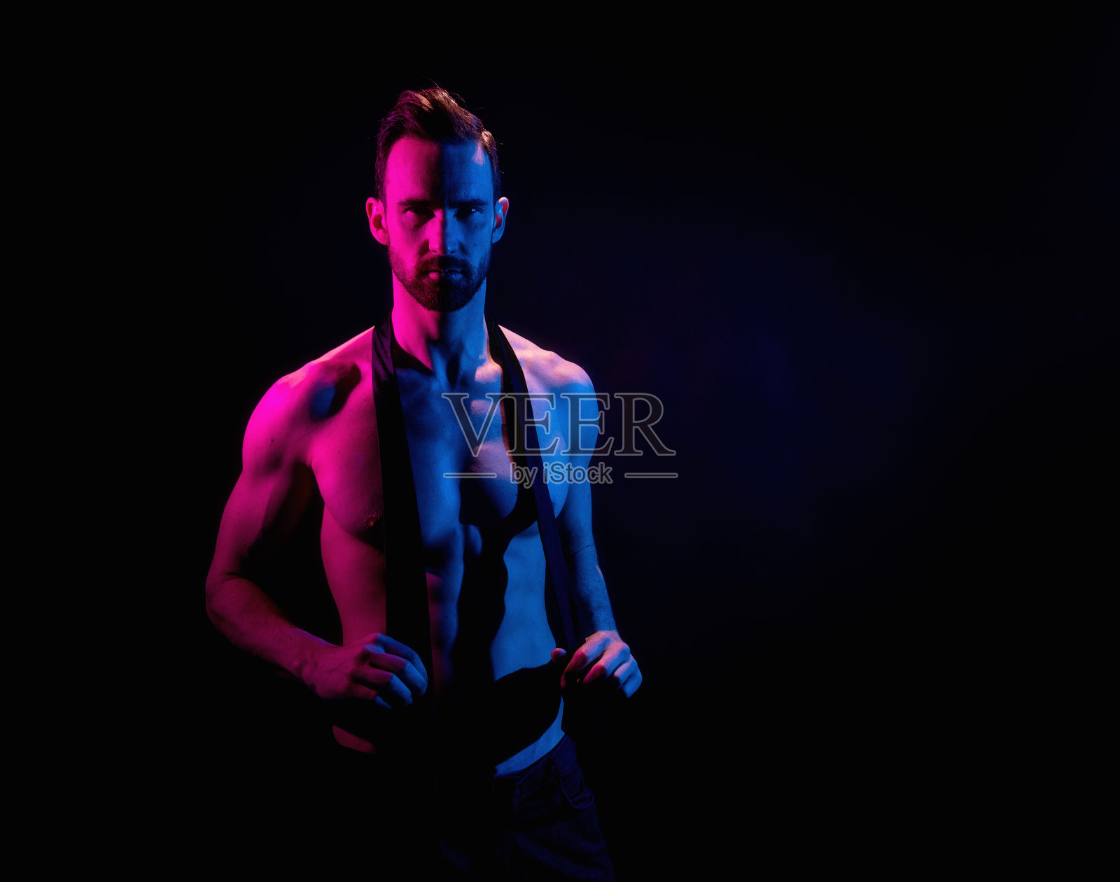 英俊的男子在黑色背景与红色和蓝色照明照片摄影图片